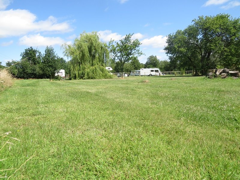 Open grass pitches with caravans parked along the far hedge.